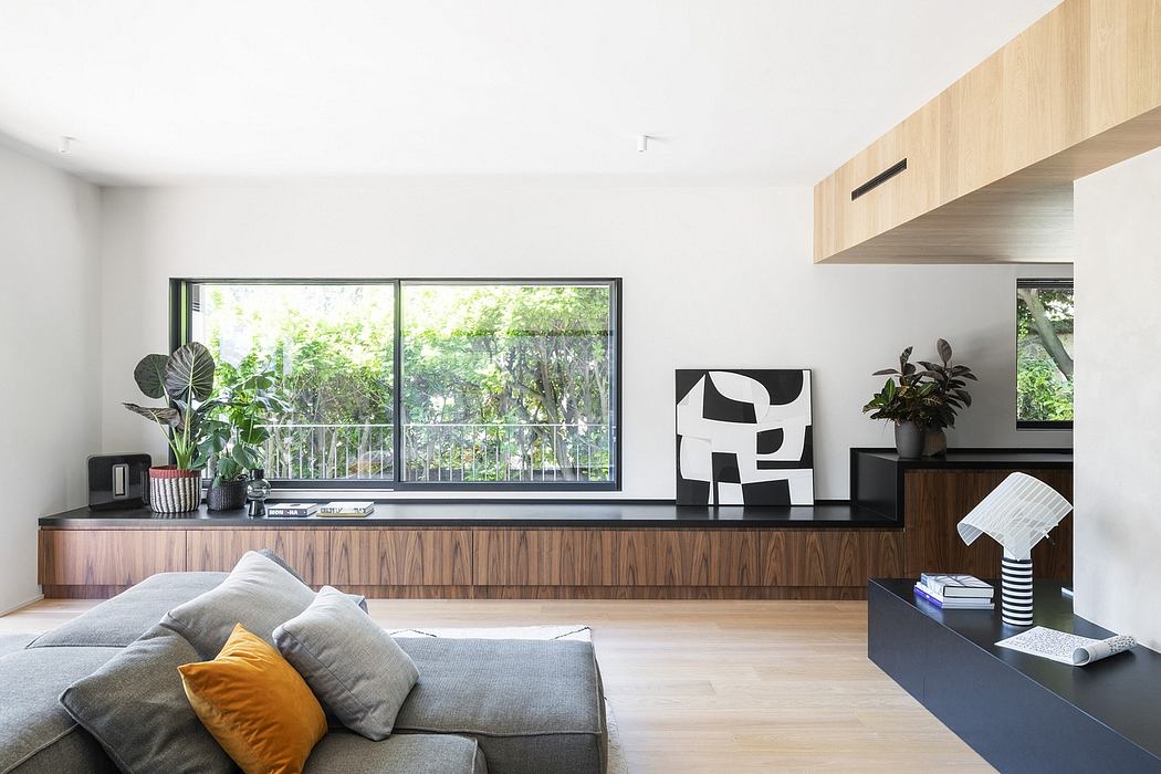 Minimalist living room with large windows, sleek wood-paneled media console, and abstract art.