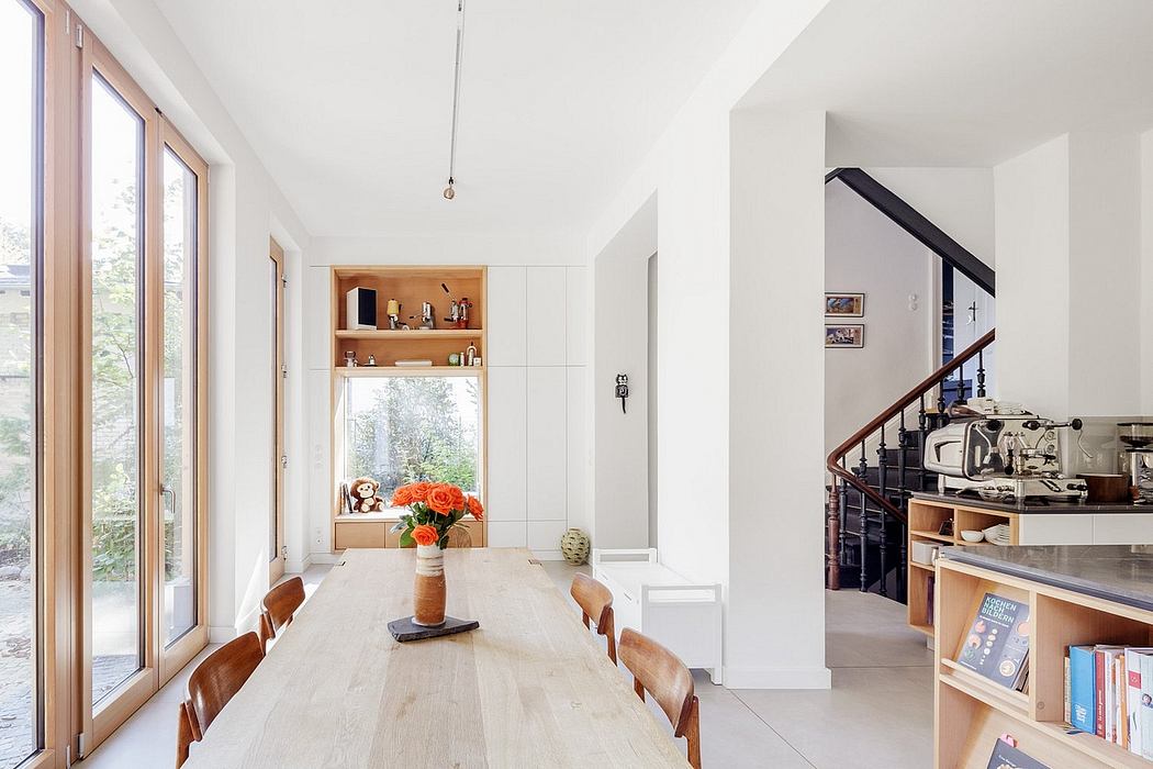 Bright, minimalist dining room with wooden table, shelves, and a view of the outdoors.