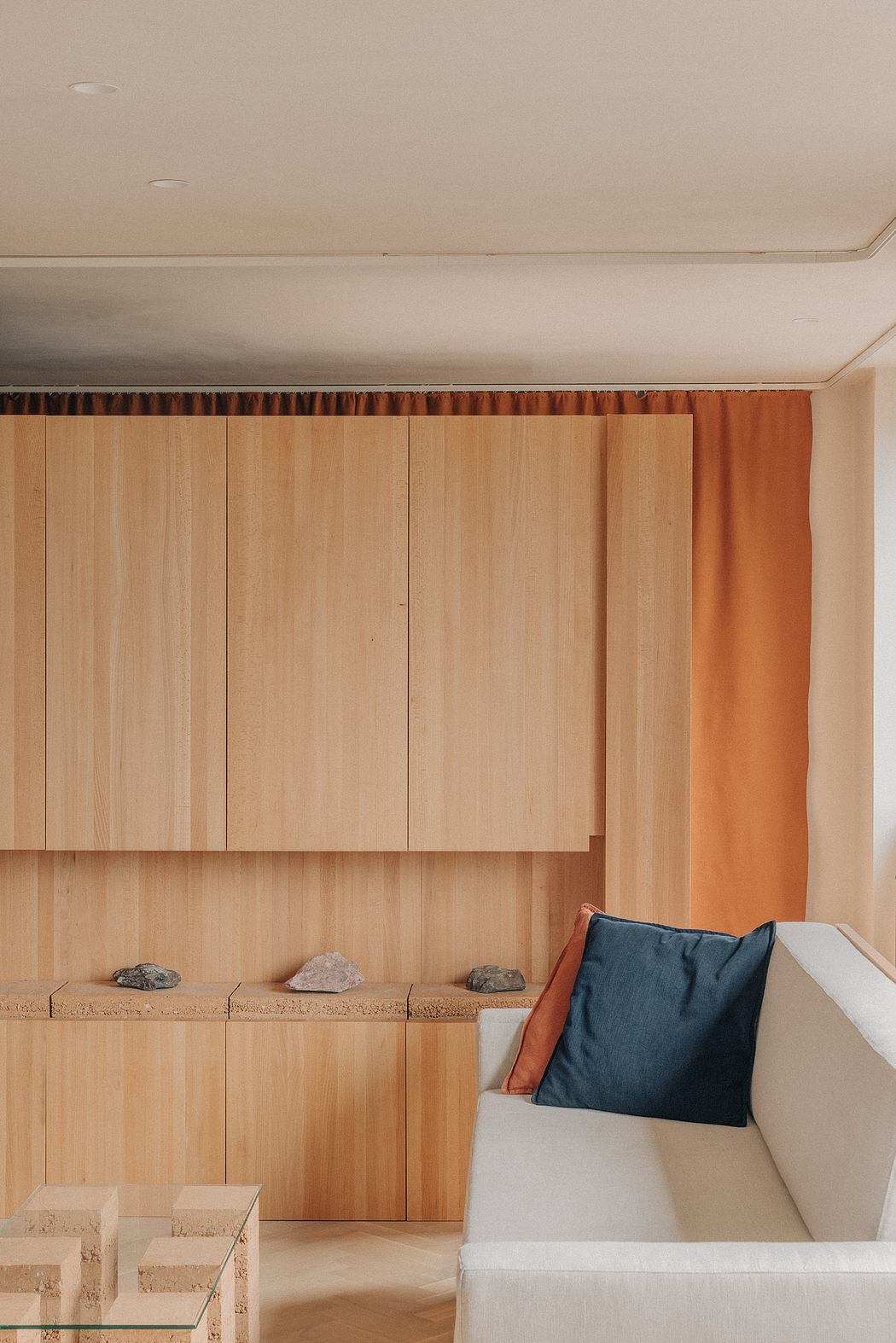 Cozy modern living space with wooden panels, textured pillows, and decorative rocks.