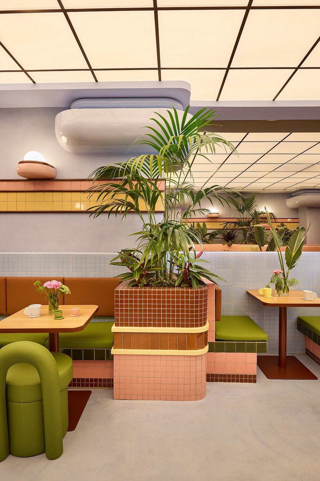 A modern, geometric cafe interior with tiled walls, wooden tables, and lush potted plants.