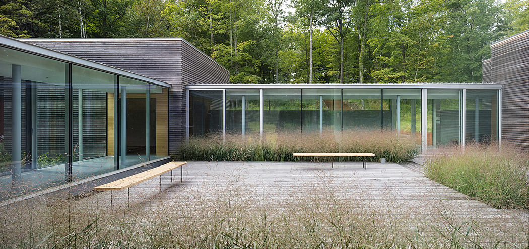 A modern glass and wood structure surrounded by a lush, forested landscape.