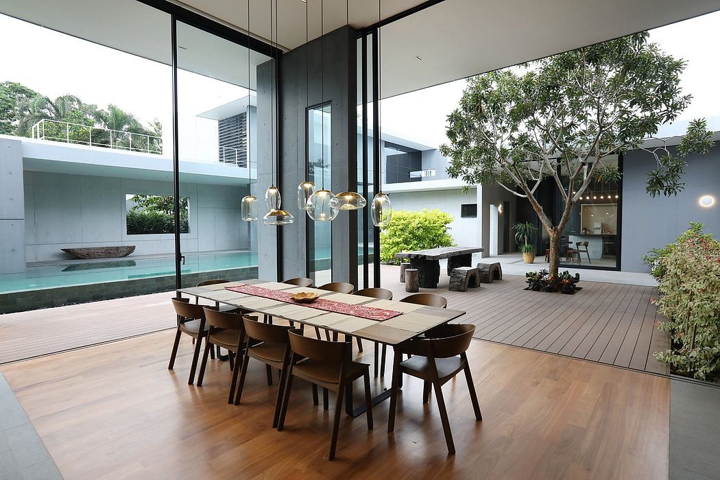 Spacious open-concept living area with floor-to-ceiling windows, wooden decking, and lush outdoor greenery.