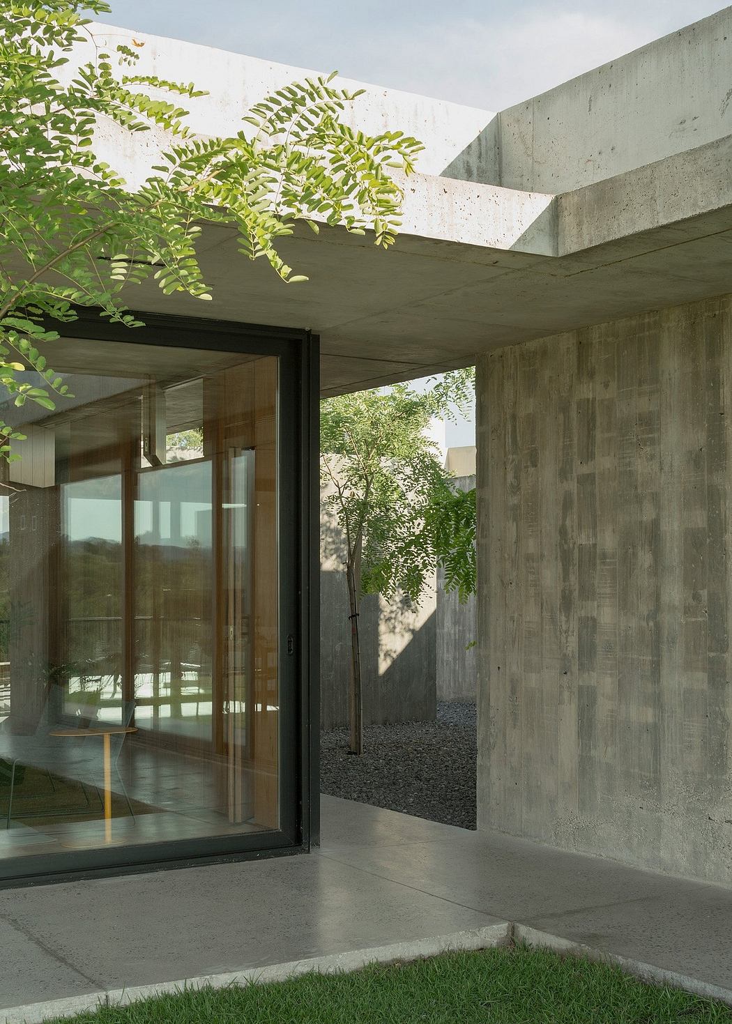 Concrete structure with lush foliage, glass walls, and a minimalist, modern aesthetic.