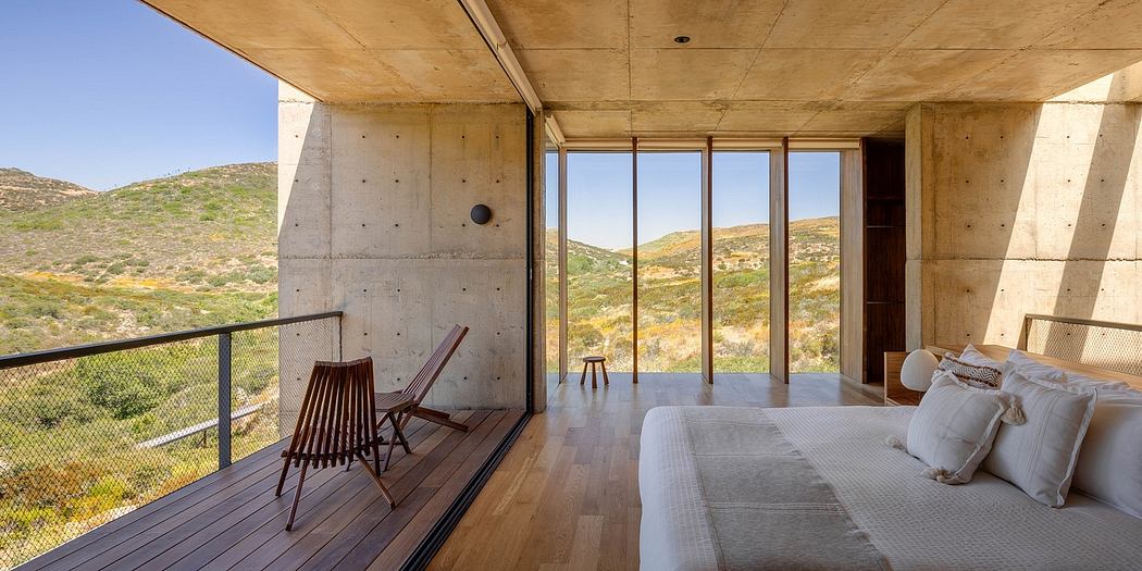 Expansive concrete interior with panoramic mountain views, modern wooden furnishings.