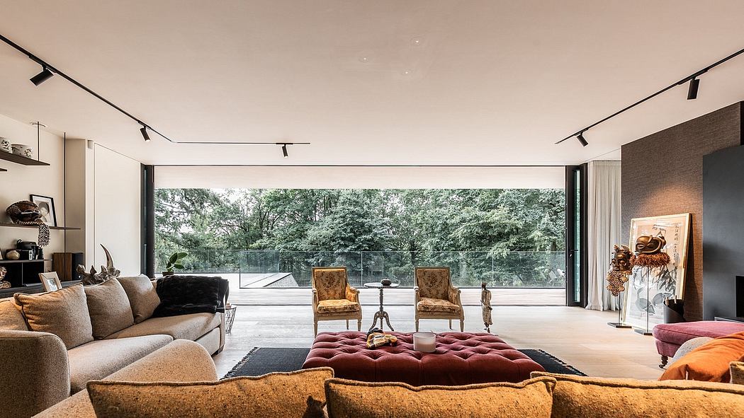 Spacious living room with large windows offering views of lush greenery and track lighting.