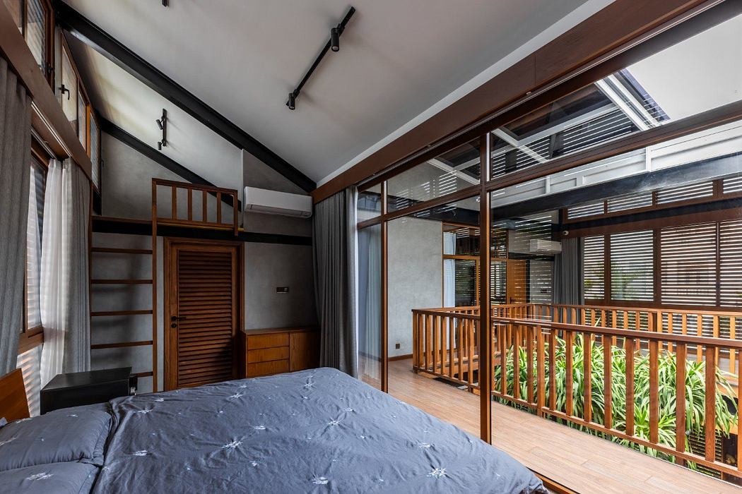 A spacious and modern bedroom with wooden beams, large windows, and a balcony.