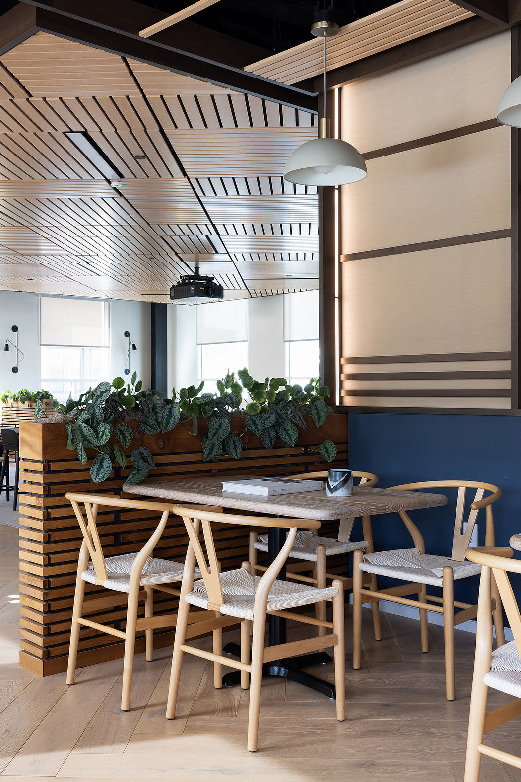 Contemporary dining area with wooden beams, upholstered chairs, and potted plants.