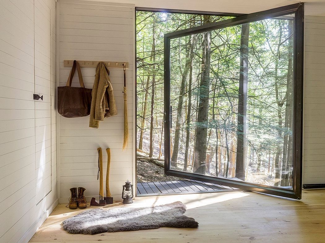 Cozy cabin interior with floor-to-ceiling windows overlooking a lush forest, wooden accents, and rustic decor.