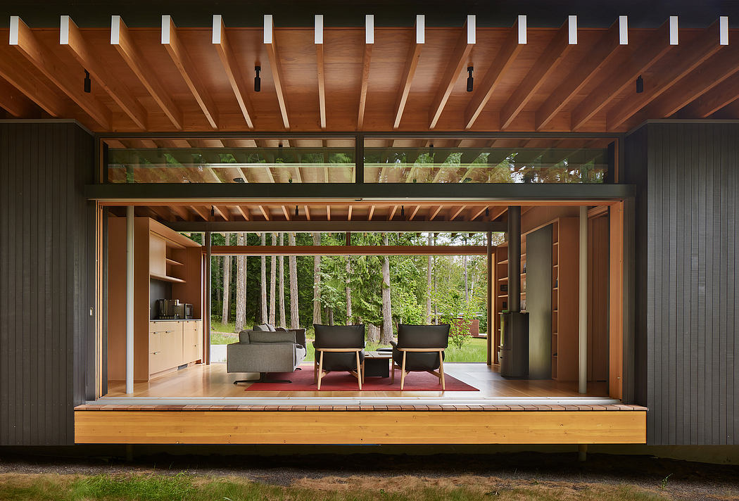 A modern wood-framed structure with large windows overlooking a lush forest landscape.