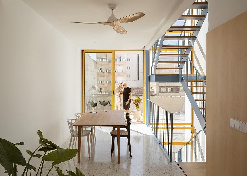 Modern open-concept interior with wooden table, metal stairs, and balcony view.