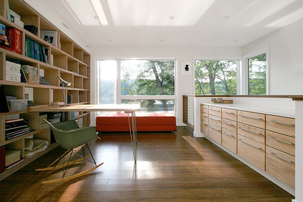 Bright, airy room with wooden shelving, furniture, and large windows overlooking trees.