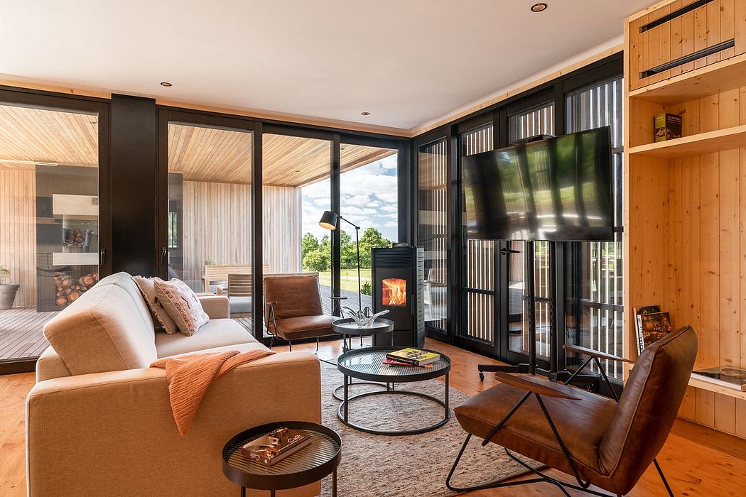 Cozy modern cabin interior with large windows, wood paneling, and a fireplace.