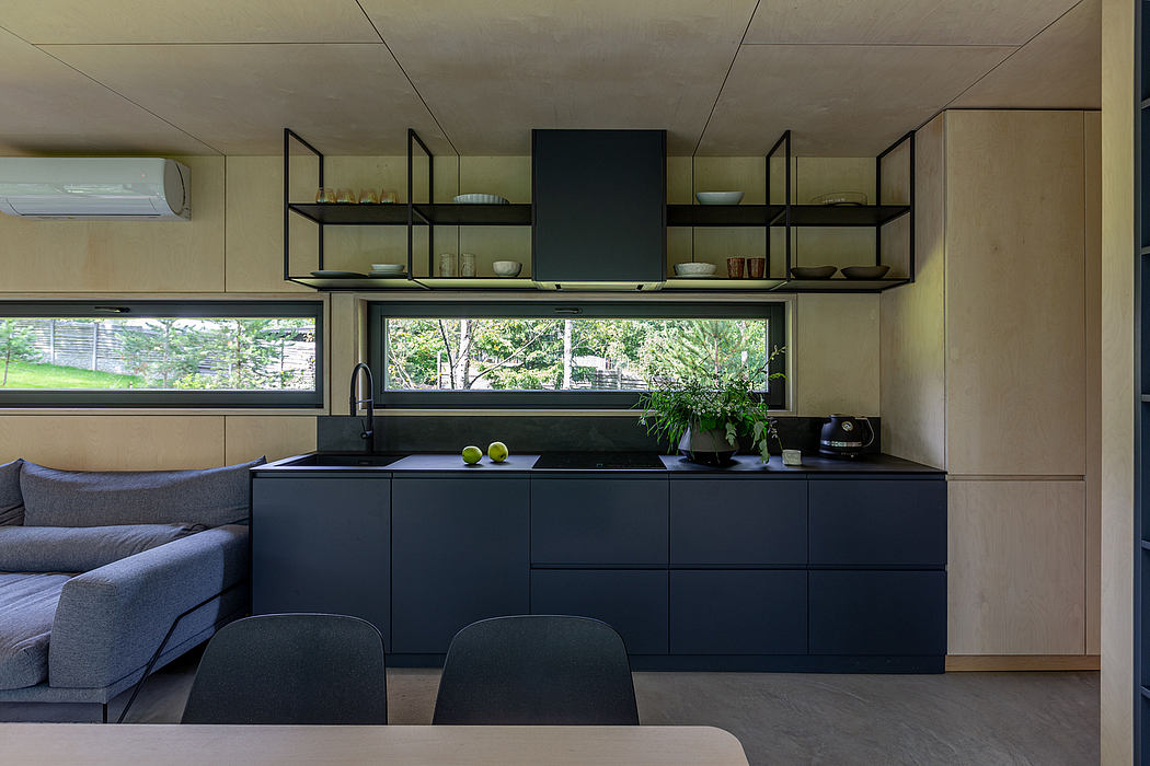 Modern kitchen with minimalist black cabinetry, open shelving, and large window overlooking greenery.
