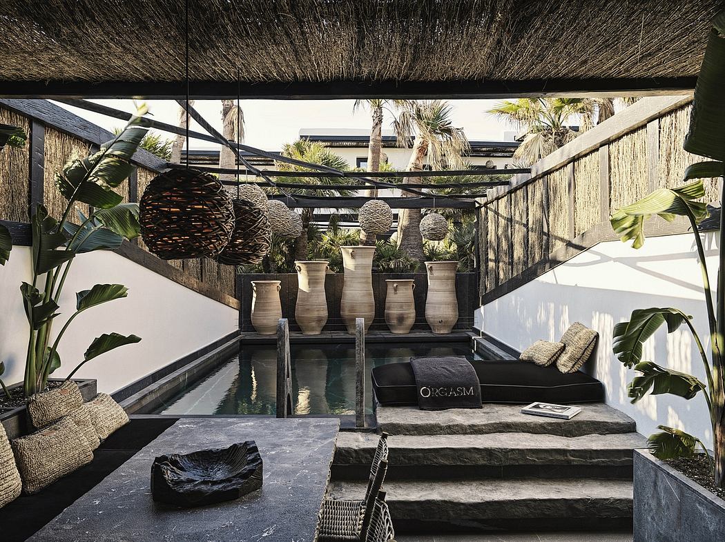 Lush tropical outdoor lounge with thatched roof, water feature, and modern decor.