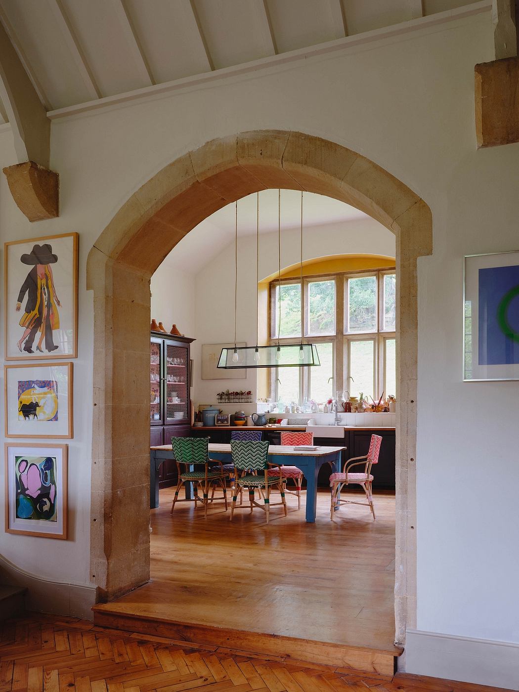 Charming arched entryway leads to vibrant, eclectic kitchen with vibrant artwork.