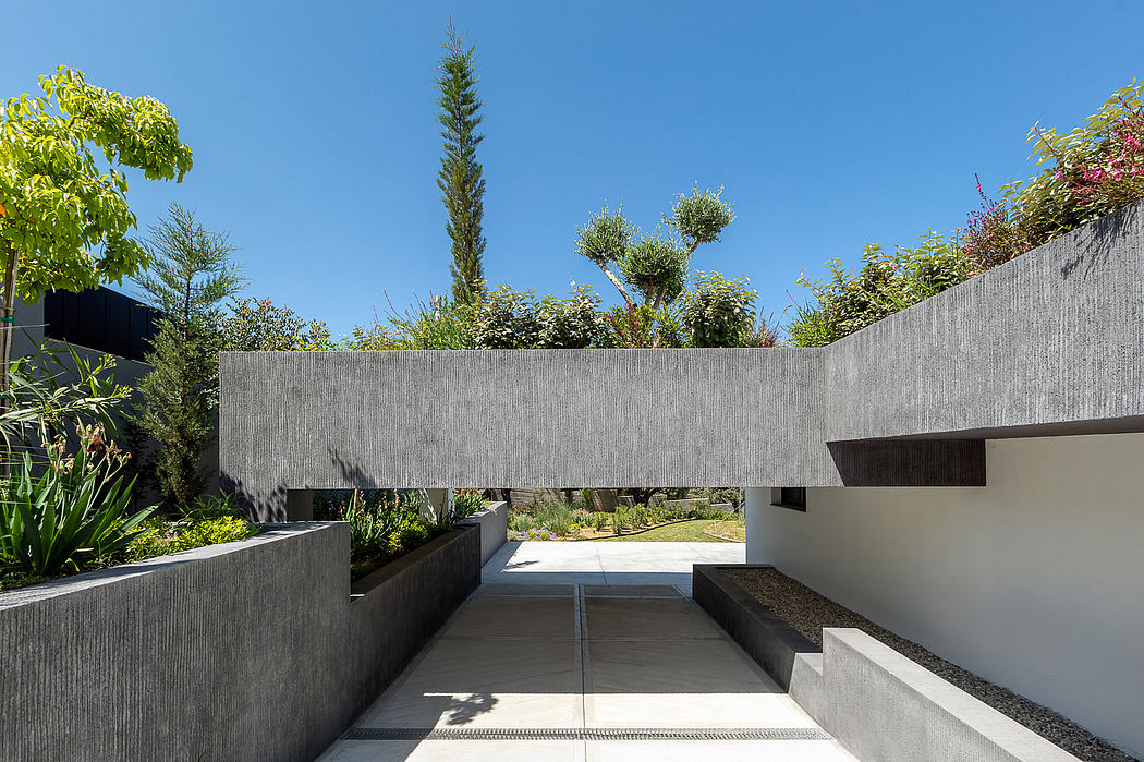Minimalist architectural design with concrete structures, greenery, and clear walkway.