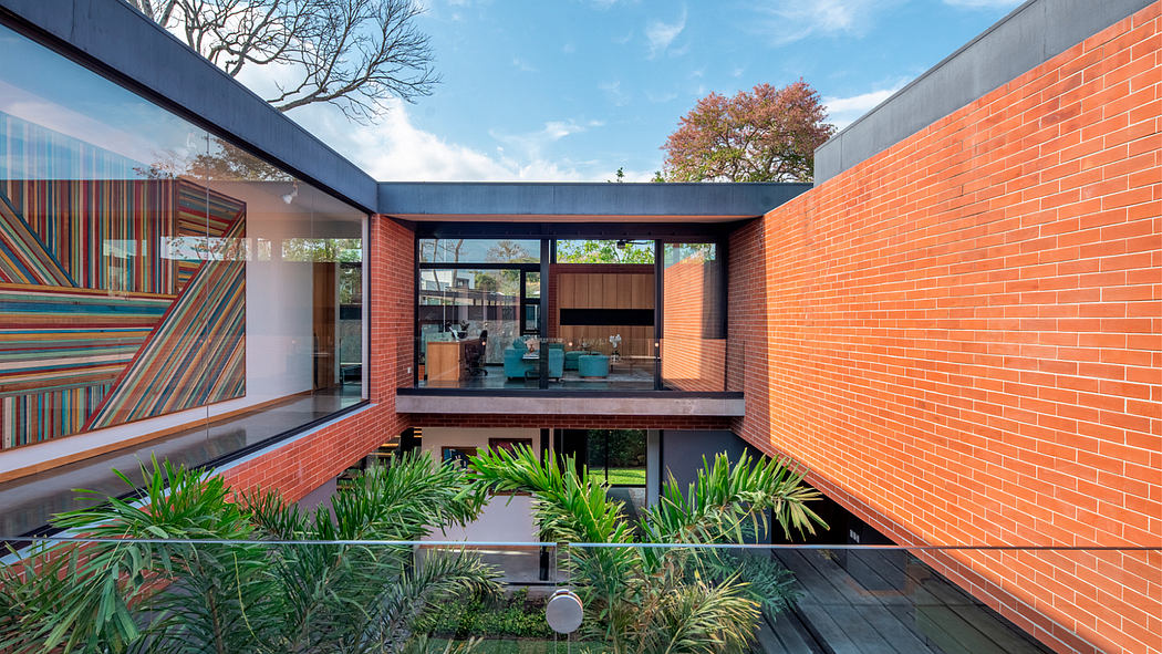 A modern architectural design with colorful, patterned glass walls, brick exterior, and lush greenery.