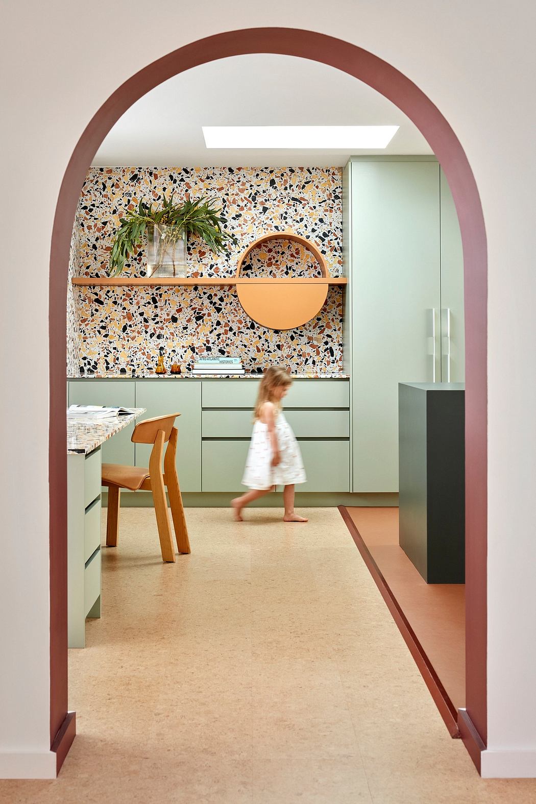 Vibrant kitchen space with terrazzo tiling, arched entryway, and minimalist furnishings.