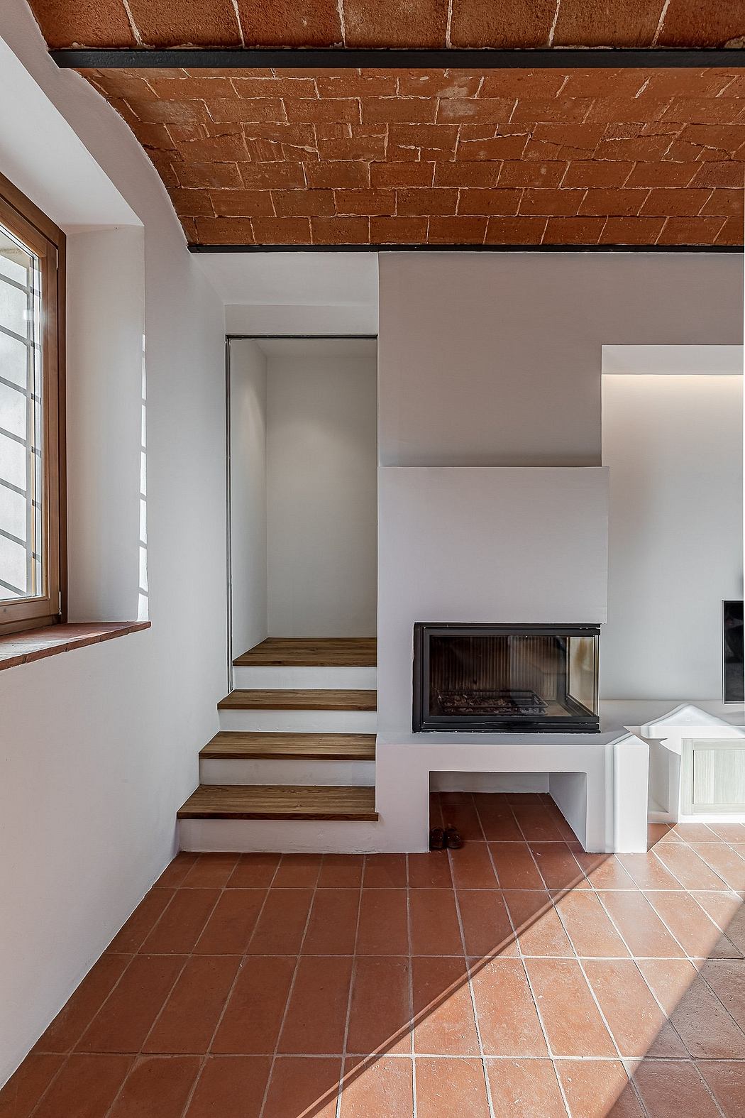 Rustic brick ceiling, wooden stairs, and fireplace in minimalist interior design.