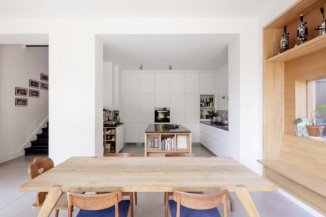Spacious, minimalist kitchen with clean white cabinetry, wooden island, and shelving.