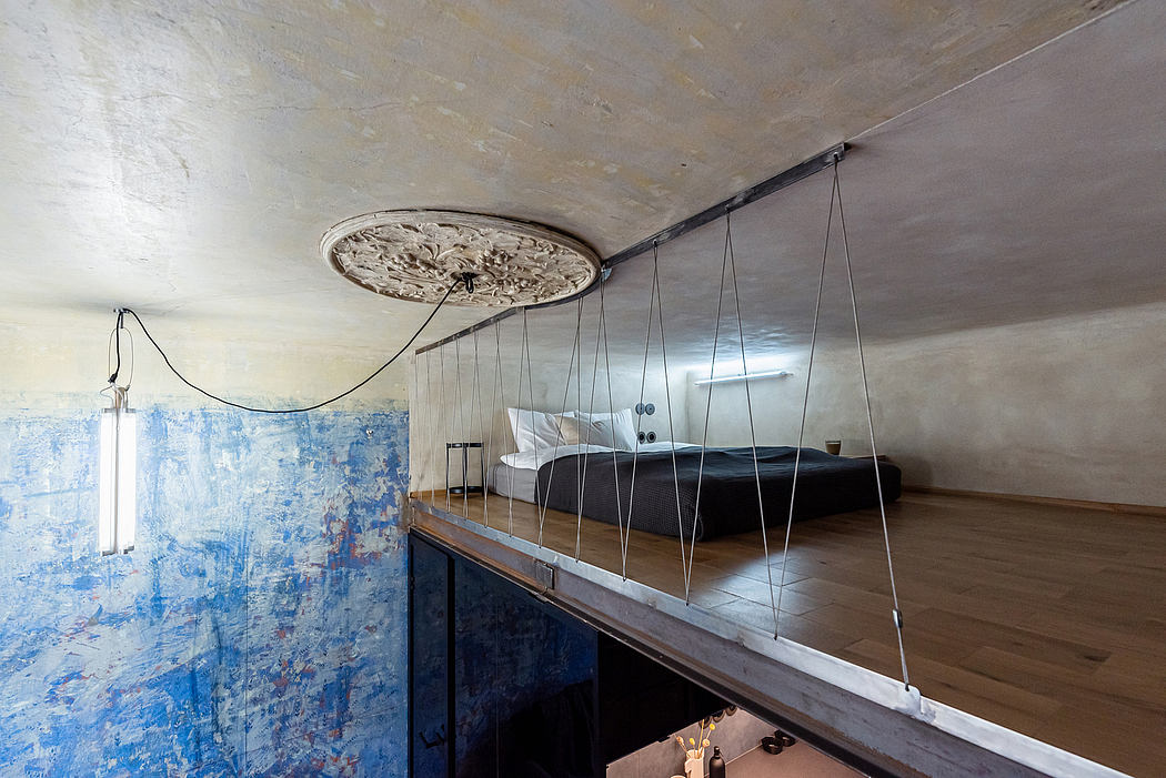 Ornate ceiling light fixture, suspended bed over raised platform, abstract blue wall.