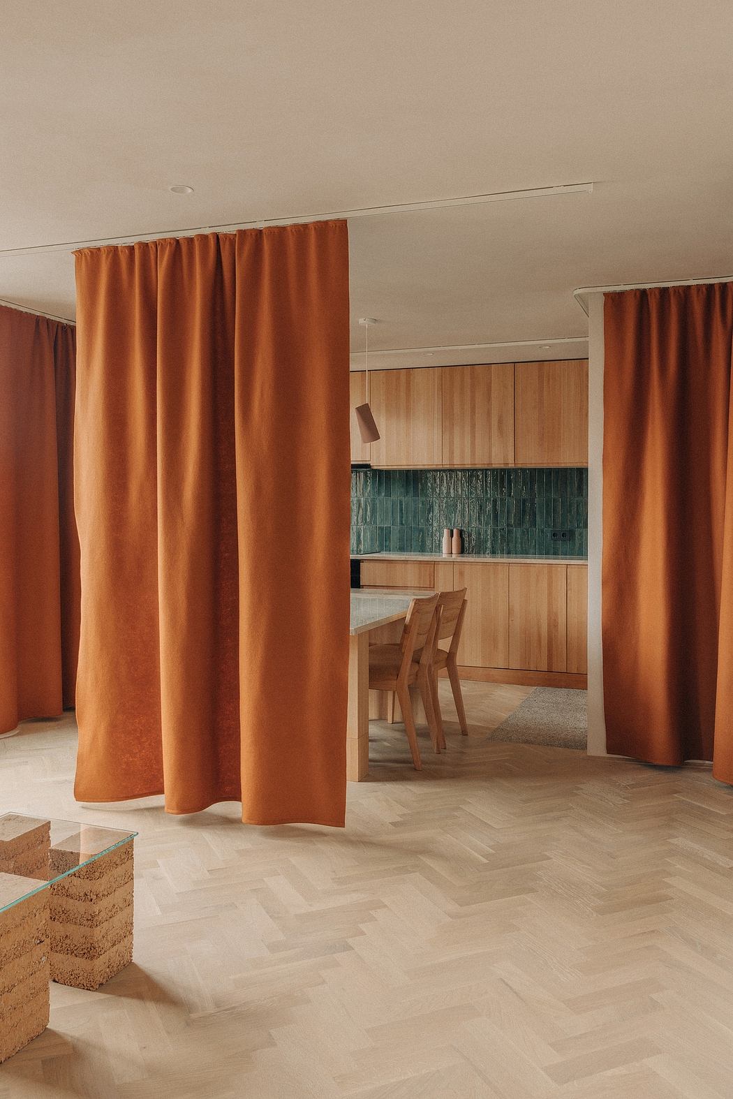 Warm, wooden kitchen with vibrant orange curtains and textured tile backsplash.