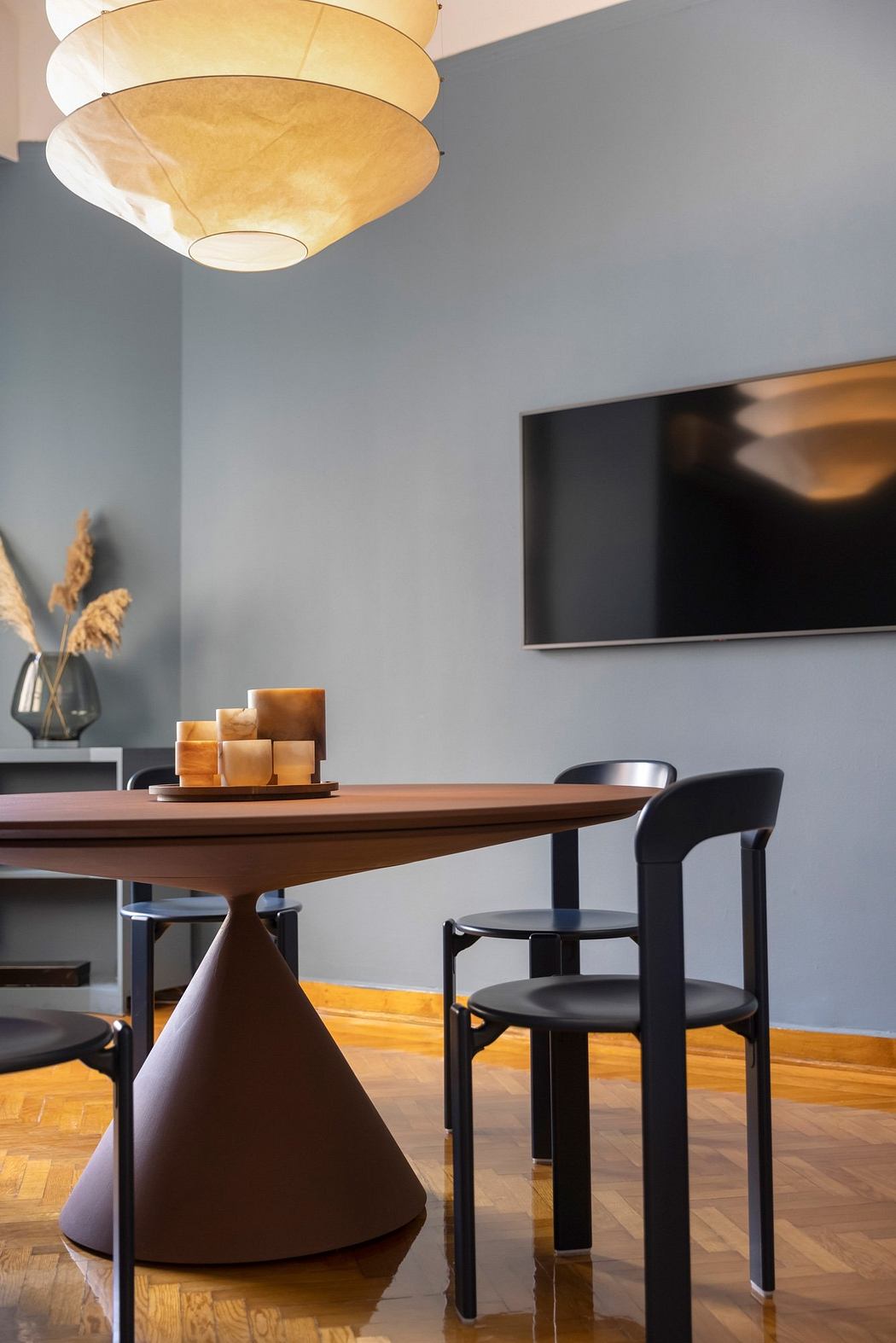 A modern dining area with a wooden table, black chairs, and a distinctive light fixture.