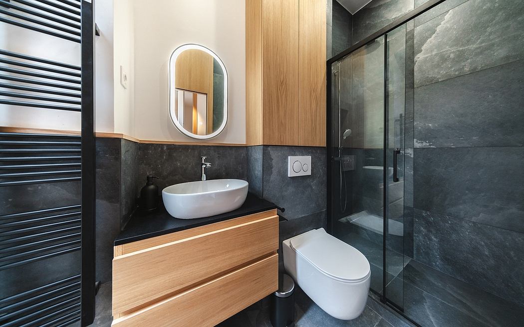 A modern bathroom with a sleek vanity, oval mirror, and a glass-enclosed shower.