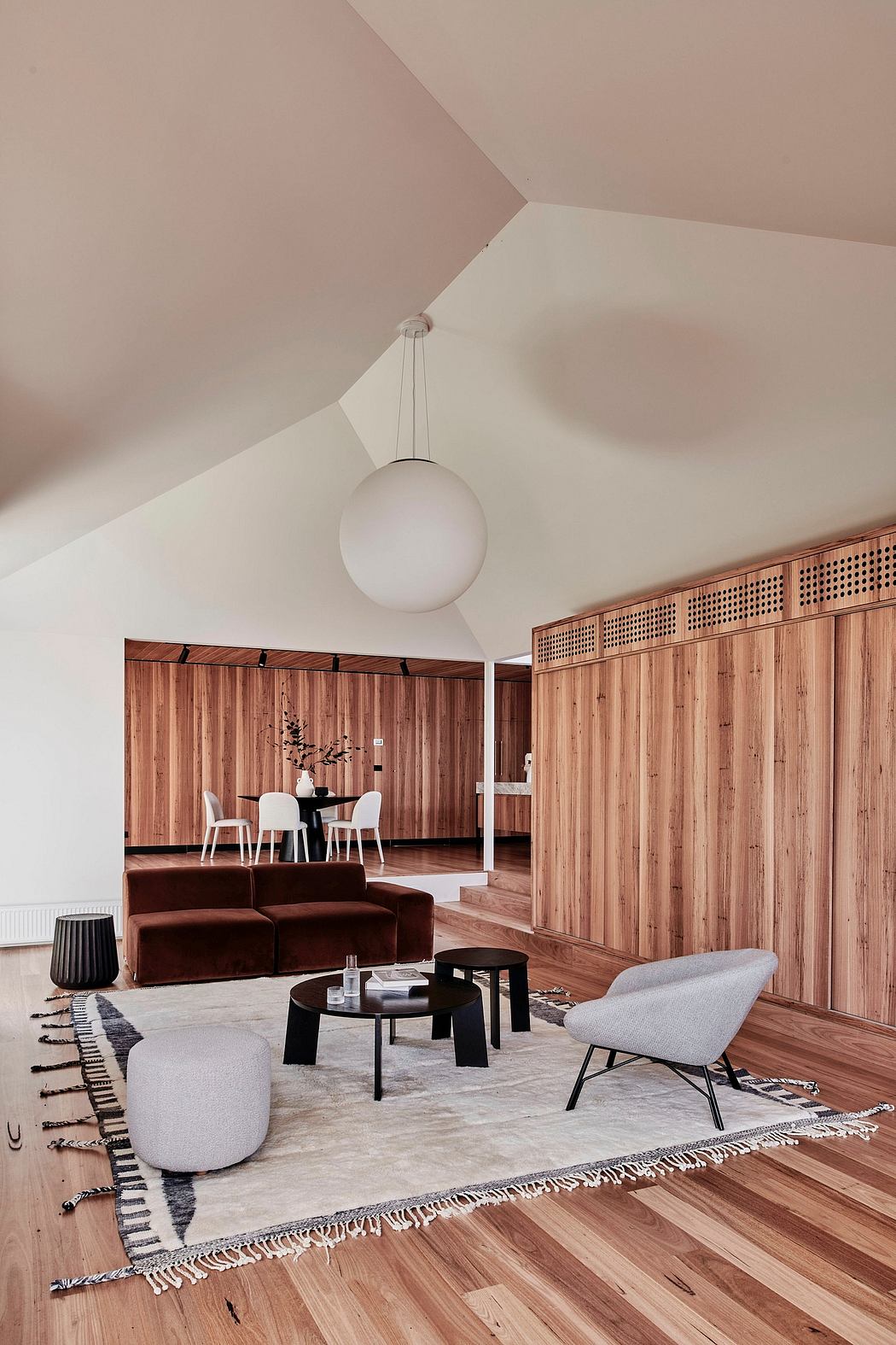 Cozy living room with wooden paneled walls, plush sofa, and modern lighting fixture.