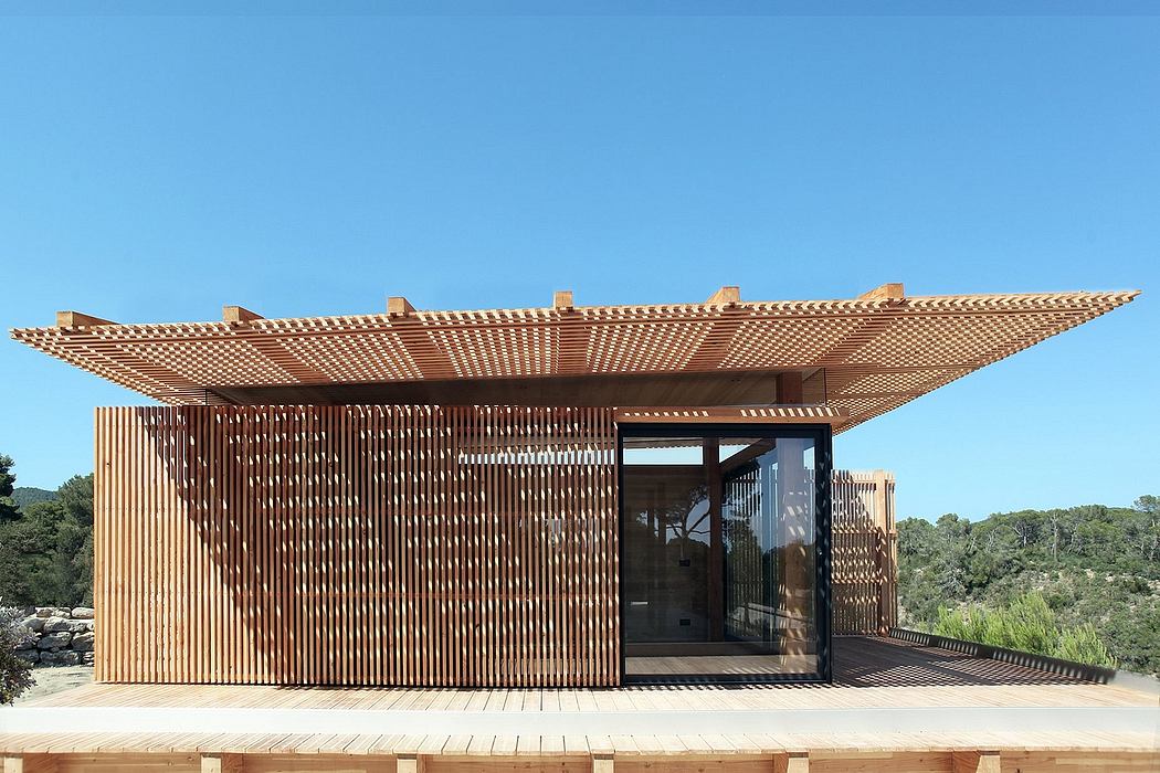 Contemporary wooden pavilion with intricate latticed roof and glass walls overlooking nature.