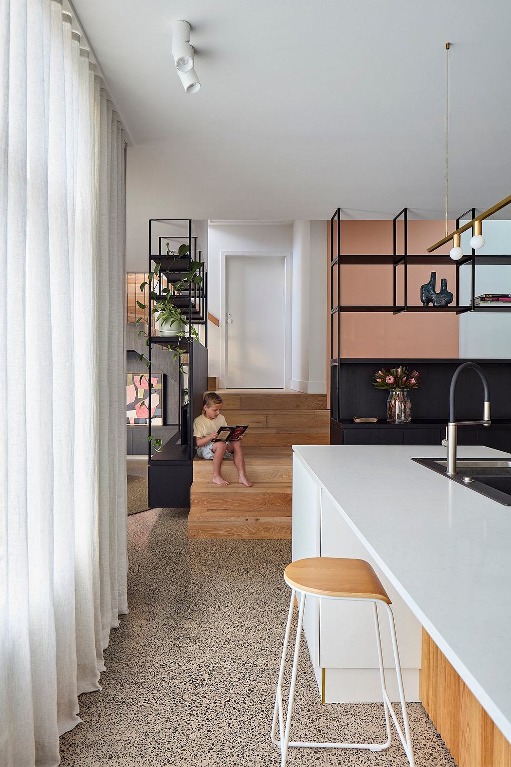 Sleek modern kitchen with geometric shelving, wood accents, and child playing on steps.