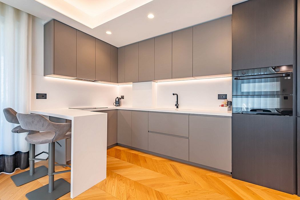 Sleek, modern kitchen with grey cabinetry, recessed lighting, and chevron-patterned hardwood floors.