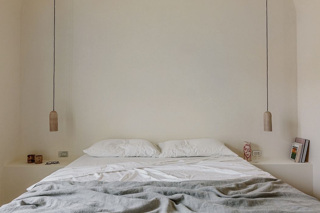 Minimalist bedroom design with pendant lighting, white bedding, and built-in shelving.