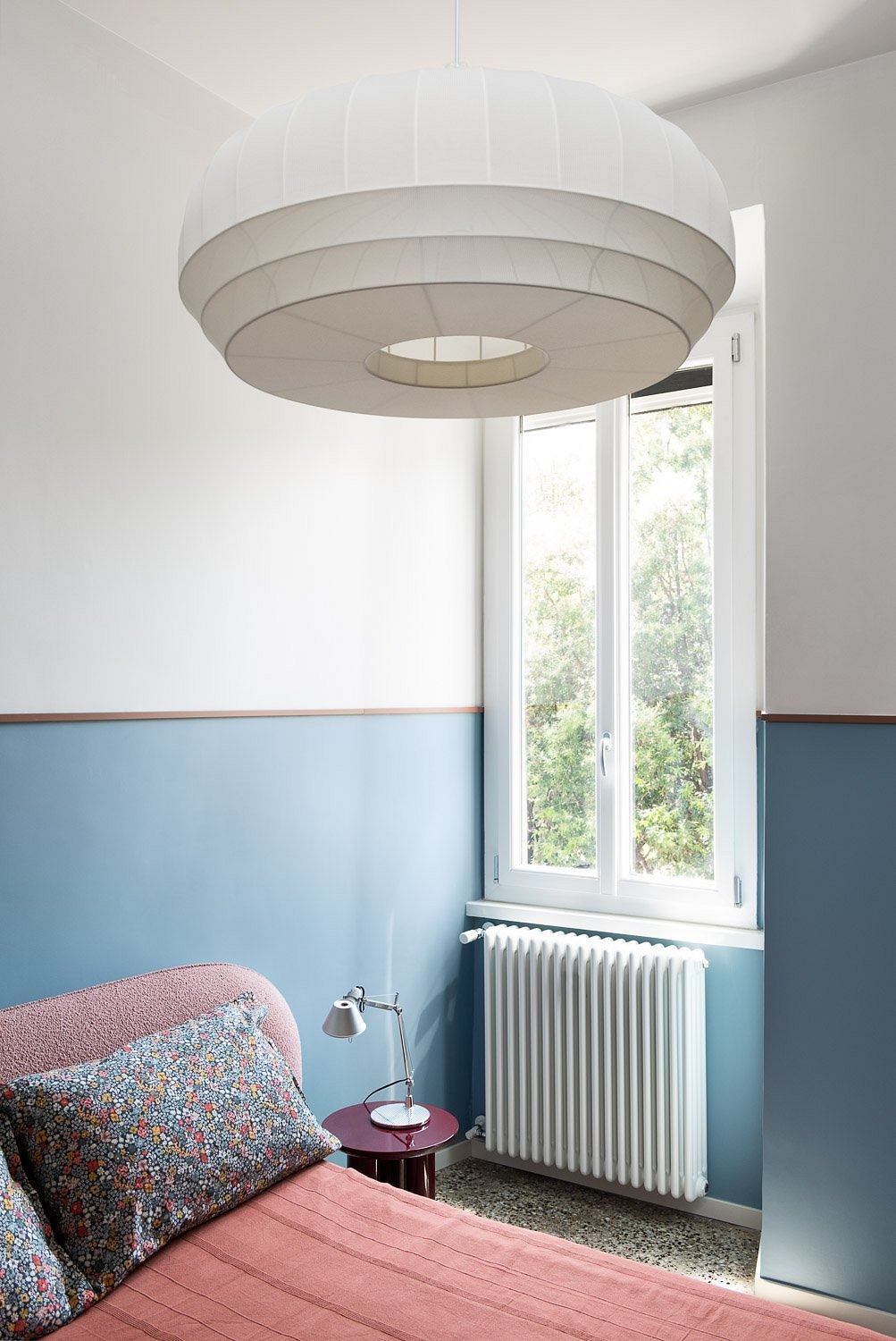 A cozy bedroom with a minimalist, modern lighting fixture and colorful accents.