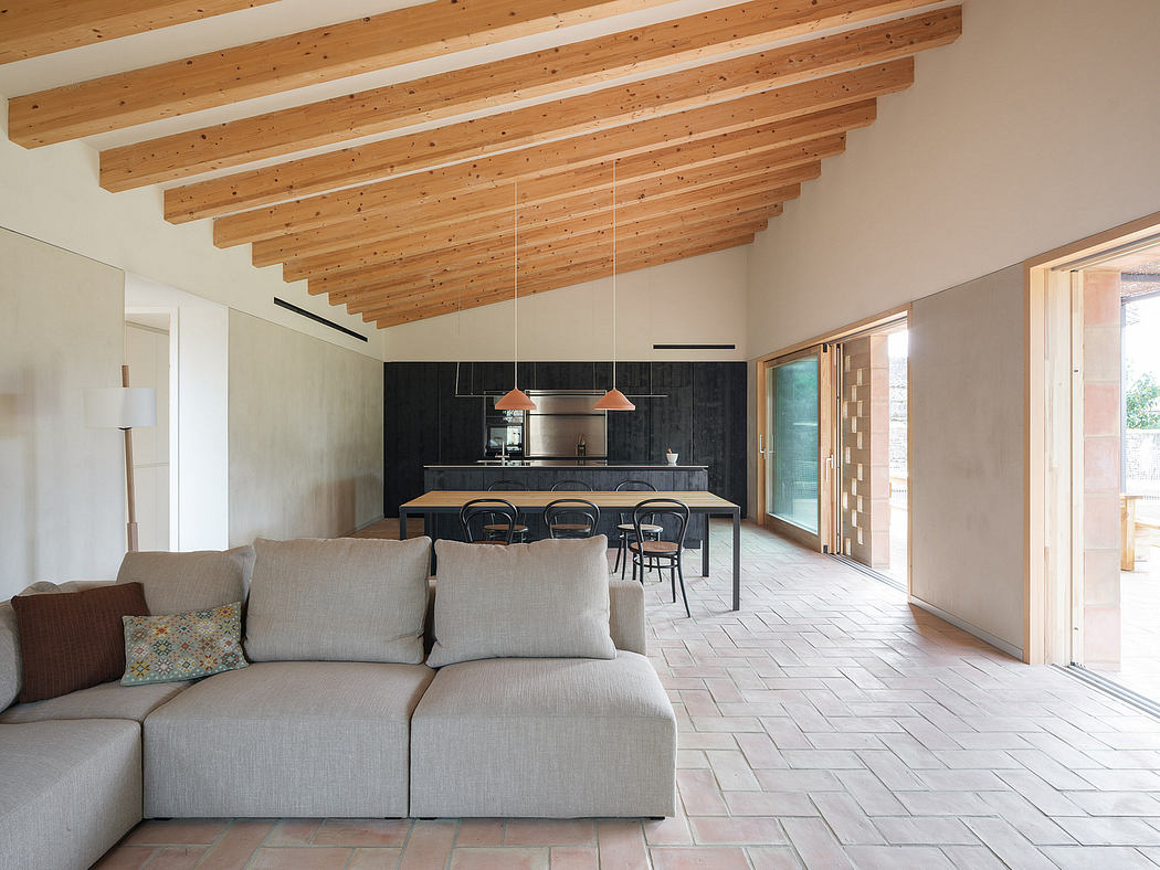 Spacious open-concept living area with wooden ceiling beams, modern kitchen, and minimalist decor.