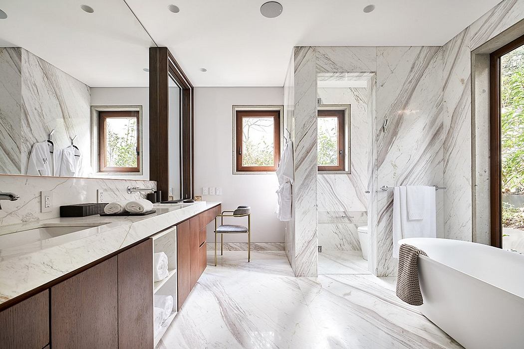 Sleek, modern bathroom with marble walls and vanity, wood accents, and large windows.