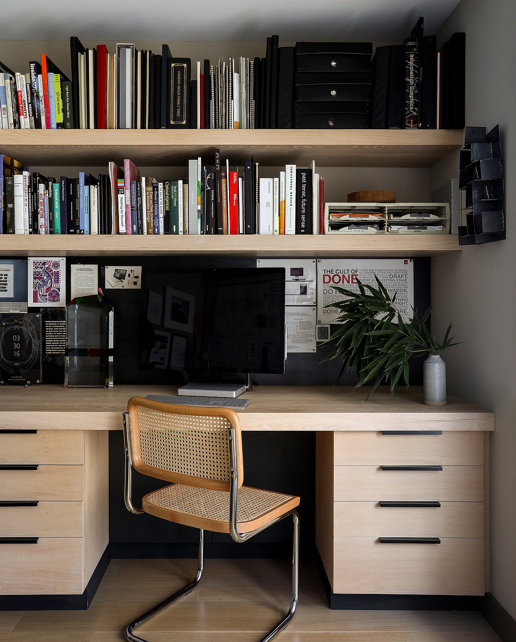 A well-organized study space with a wooden desk, built-in shelves, and a cane-back chair.