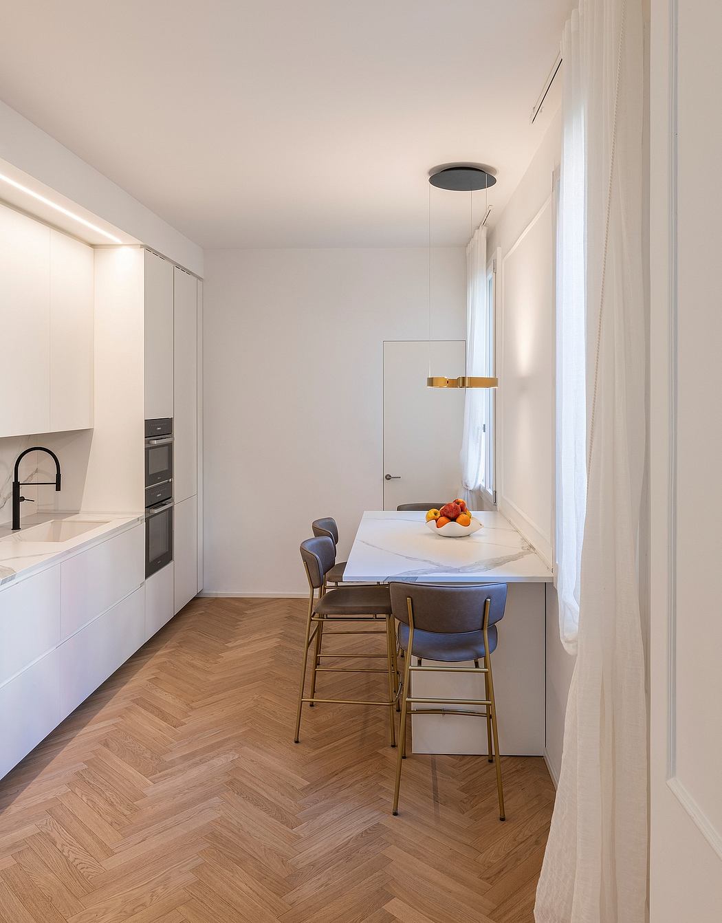 Sleek, minimalist kitchen with modern cabinetry, herringbone wood floor, and stylish lighting.