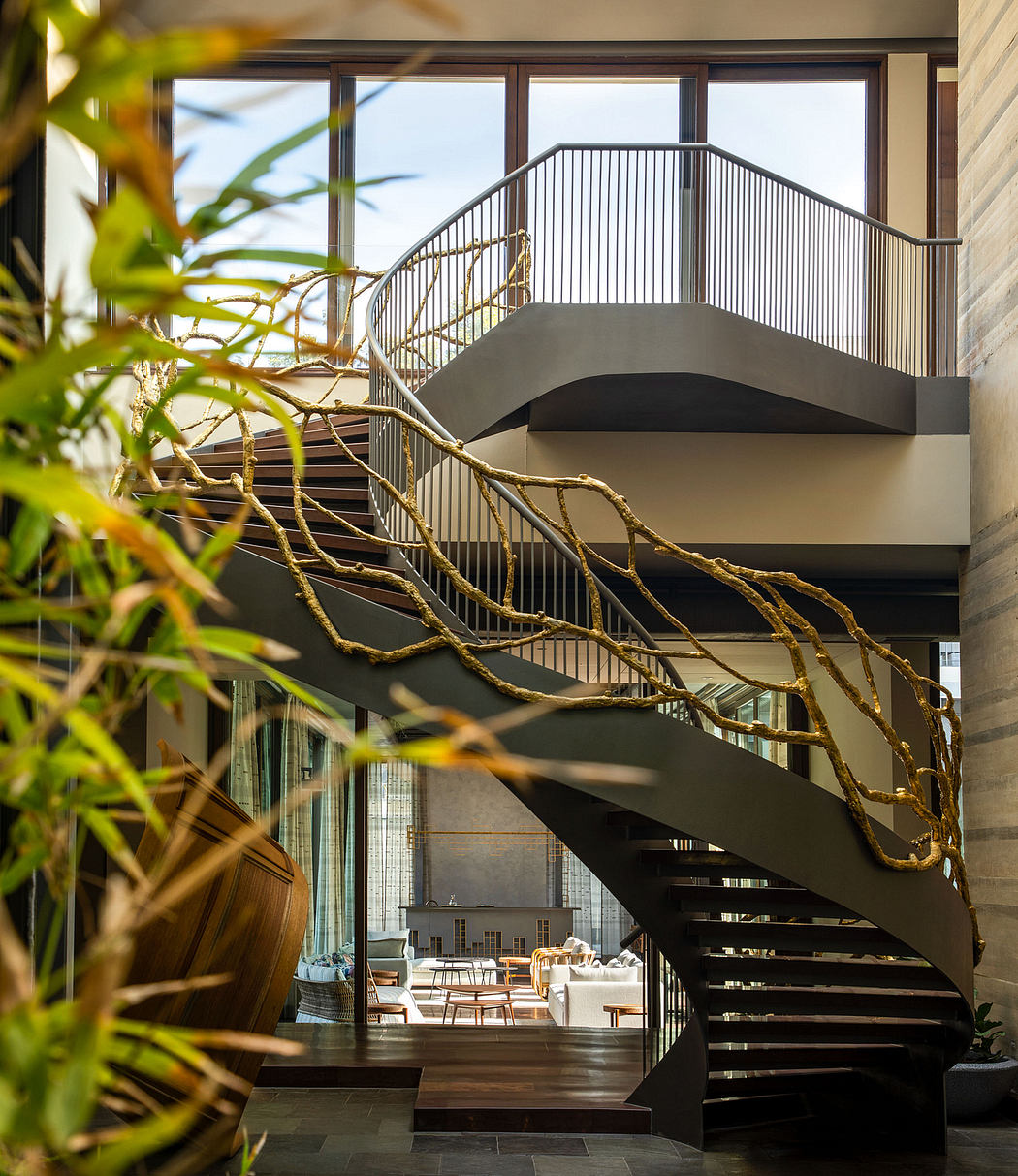 Spiral staircase with organic branch-like railing leading to glass-enclosed living space.
