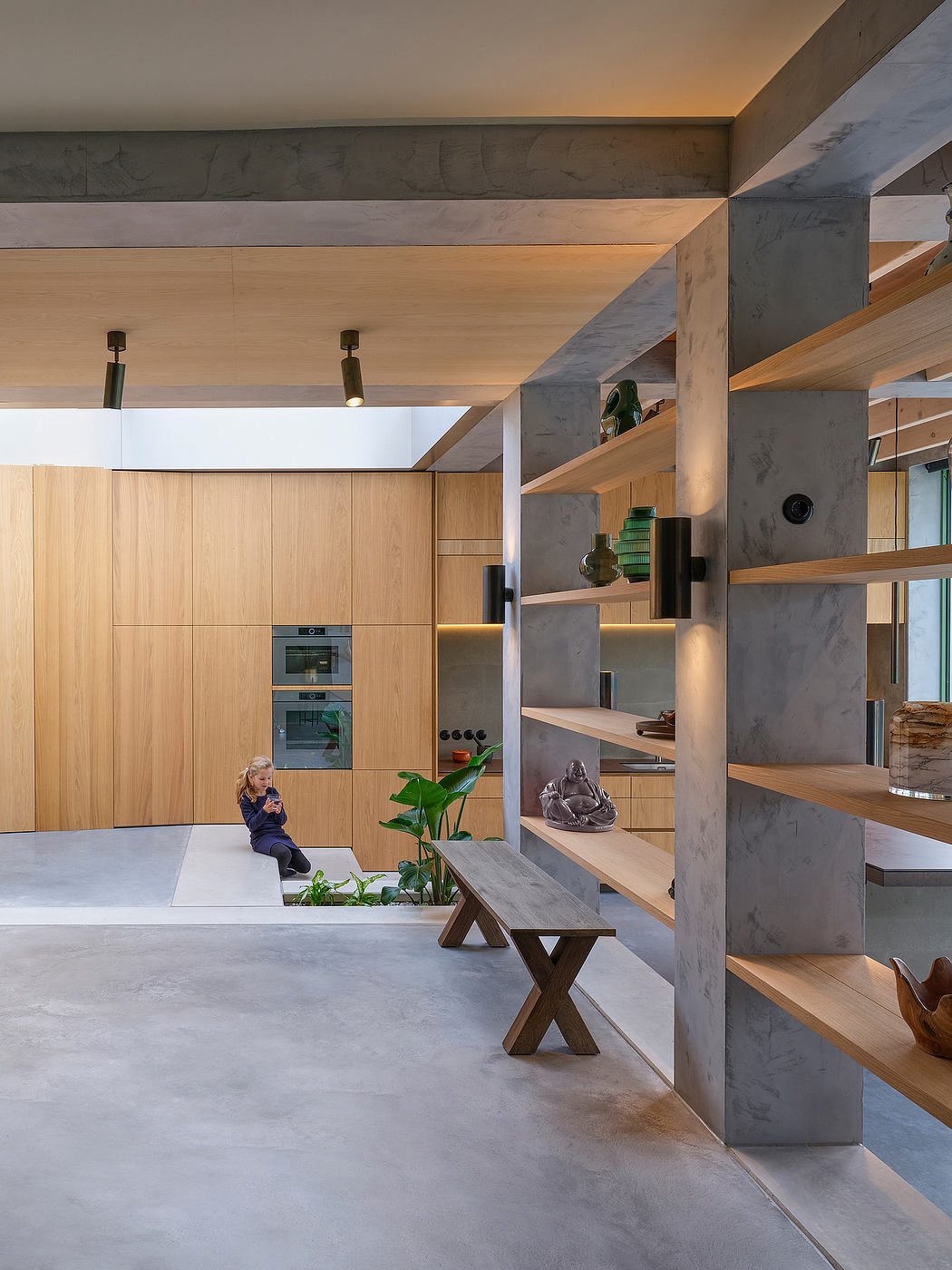 Minimalist kitchen with concrete, wood, and plant accents; open, airy design.