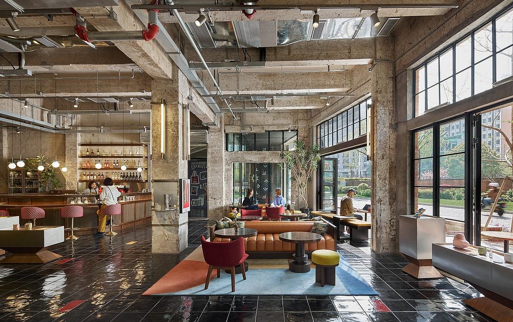 Spacious industrial-style interior with exposed beams, large windows, and diverse seating areas.