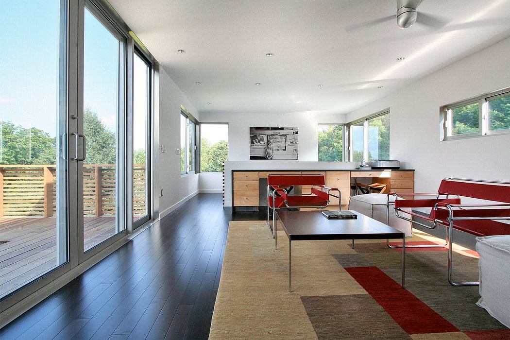 Sleek, modern interior with large windows, dark wood floors, and vibrant red accents.