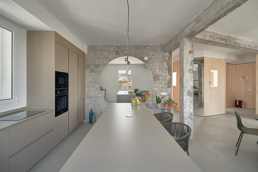 Spacious kitchen with concrete walls, minimalist cabinetry, and circular mirror.