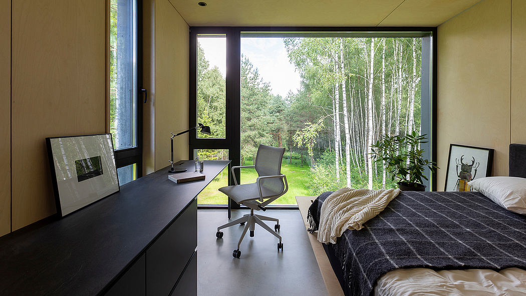 Spacious bedroom with large windows overlooking a forested landscape and modern furnishings.