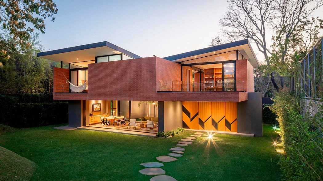 Modern multi-level house with brick and glass facade, illuminated outdoor path.