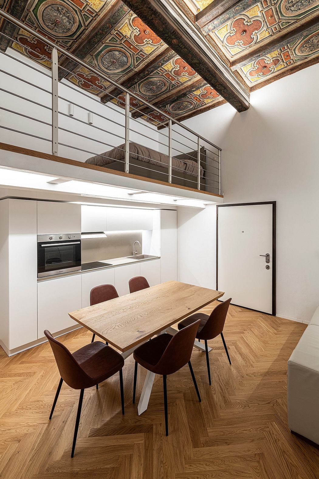 A modern kitchen with an ornate, elaborately decorated wooden ceiling. Sleek white cabinets and a rustic wooden dining table.