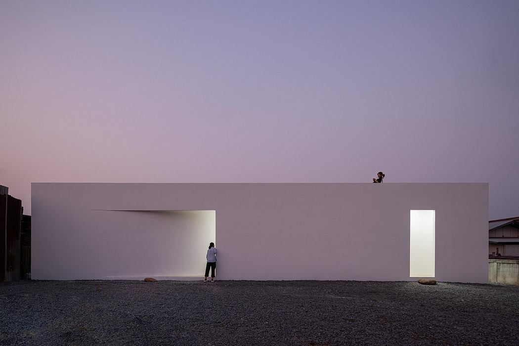 Minimalist architectural composition with recessed doorways, silhouetted figure, and distant animal.