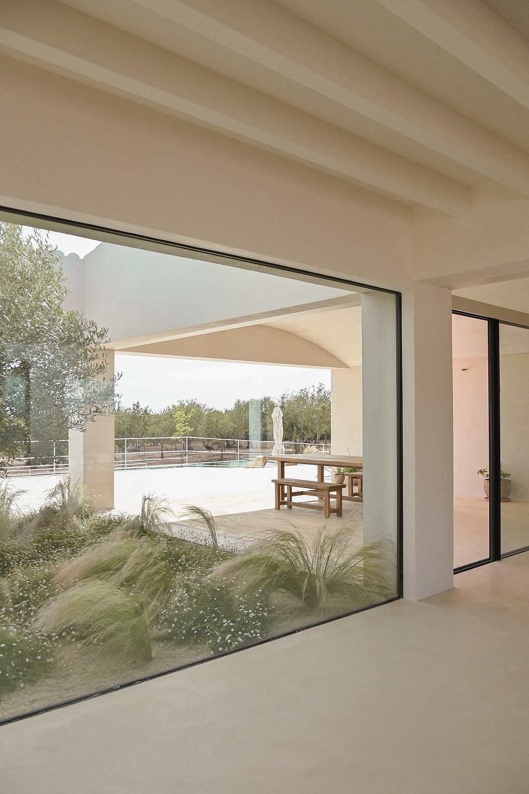 Spacious indoor-outdoor living space with floor-to-ceiling windows, covered patio, and pool.