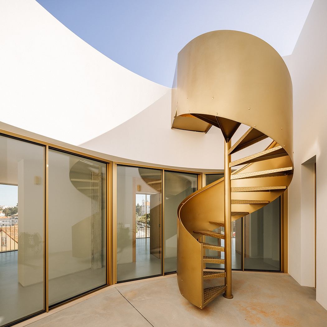 Modern spiral staircase with gold metallic finish in a bright, open interior.