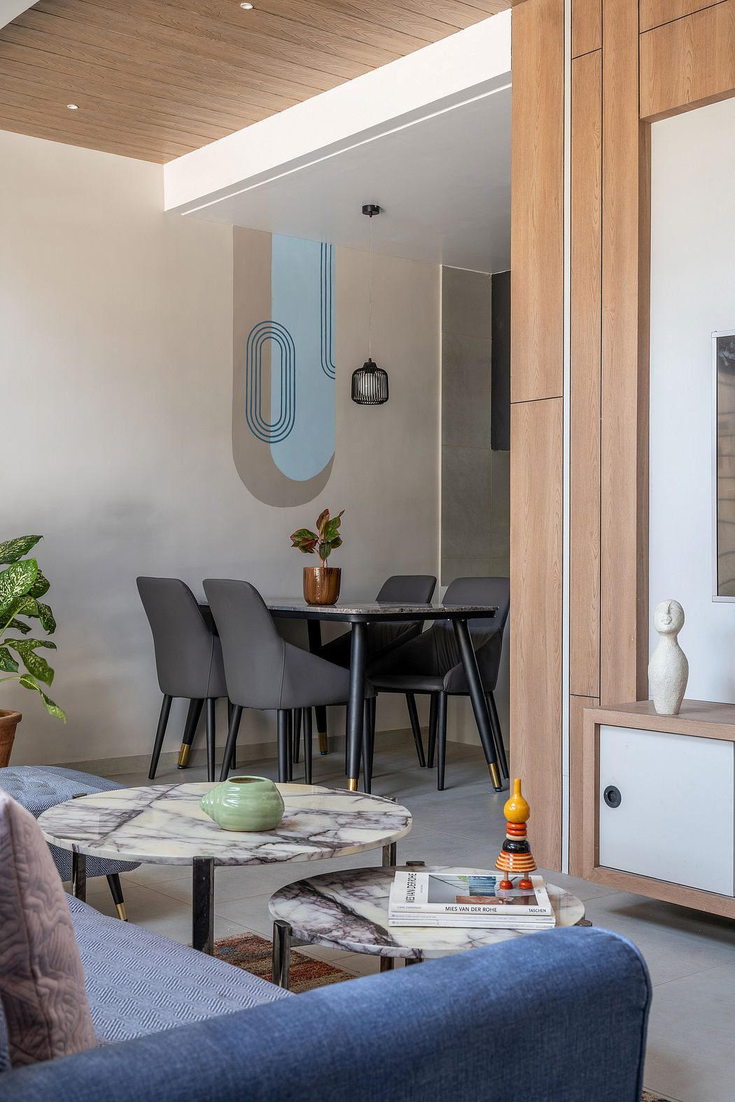 Minimalist dining space with sleek marble table, wooden ceiling, and modern decor.